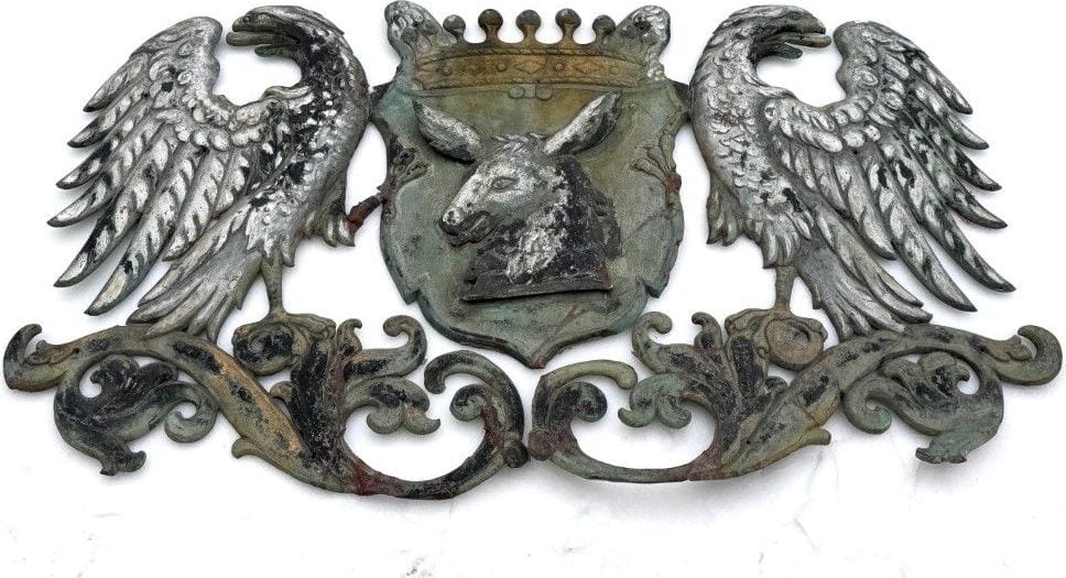 Großes Wappen aus getriebenem Metall, gekrönter Eselskopf mit Adlern als Schildhaltern